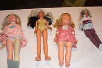 Front view of four vintage dolls ranging from 12 to 19 inches, showing details of outfits and general condition.