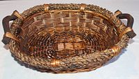 Top angled view of oval woven basket showing braided rim and wooden handles