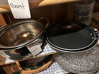 Photo showing two stainless steel bowls and two black non-stick frying pans stacked.