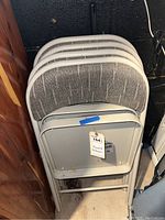 Four folding chairs stacked together, showing the backrest fabric and metal frame from a top angle.