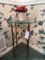 Full view of the glass top plant stand with a flower pot on top (plant not included) showing the glass surface and metal frame with decorative elements.