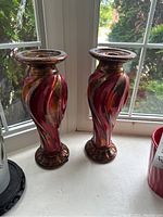 Pair of large wooden candlesticks with twisted carved design and reddish brown finish.