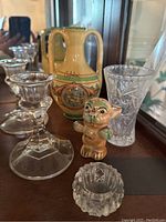 Photo showing decorative ceramic vase with handles, two faceted glass candlesticks, cut glass vase, and ceramic cat figurine