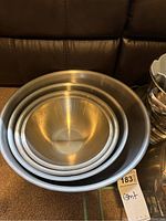 Nested stainless steel mixing bowls in three sizes, smooth and round shaped.