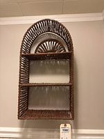 Wall-mounted wicker hanging shelf with two shelves and an arched woven top design.