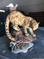 Side view of the porcelain tiger liquor decanter showing the tiger positioned on a tree branch with detailed spots and tail extending, standing on a snow-covered base.