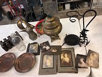 Wide view showing all items on table: brass samovar, antique photos, copper plates, metal poker stand, poker, glass bottle, metal chip rack