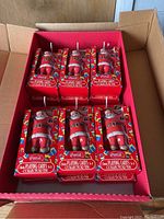 Photo of a sealed case box containing six Coca-Cola Santa collector tins, each with 2 decks of playing cards.