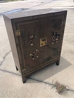 Full view of the Oriental table cabinet stand showing front painted doors with traditional Asian figures and nature elements, metal lock hardware and aged wood.