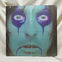 Front cover showing a die-cut design forming a blue-painted face with purple makeup around the eyes and mouth.