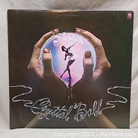 Front cover of Styx Crystal Ball vinyl album showing hands holding a glowing crystal ball with dancer figure inside.