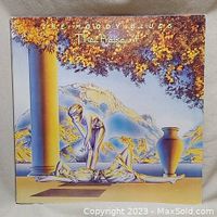 Front cover of The Moody Blues 'The Present' vinyl album featuring artistic landscape artwork with classical columns and figures.
