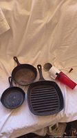 Three cast iron pans and a vintage bullet ice crusher with red and white colors