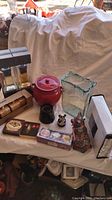 Various home decor items including ceramic canister, glass vase, figurines, candle holders, and biscotti box arranged on a table