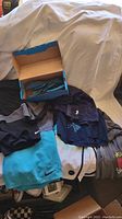 Photo showing multiple pairs of swim trunks and basketball shorts with Speedo flip flops box.