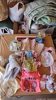 Lot items arranged on a bed including bibs, socks, hats, pajamas, and Disney lovies in snow globes