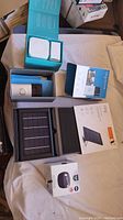 Multiple smart home devices including Ring Video Doorbell and solar panel charger visible in original packaging with other smart speaker devices