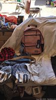 Photo of new pink Eastport backpack with tags and assorted casual women's clothing including gray 'LOVE' sweatshirts, white blouse, denim, and black garment.
