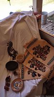 Metal Kokopelli sculptures, signed terracotta vases, and three storyteller placemats arranged on a white cloth.
