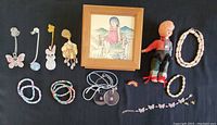 Complete overview of all jewellery pieces, doll, framed print, and wood box on black background