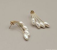 Pair of 10kt gold earrings each with 5 white freshwater pearls arranged in a curved spray design, laid flat on a neutral background.