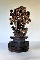 Front view of the hand carved Asian soapstone tree sculpture on a stone base showing intricate leaf, animal and bird carvings and the carved base.