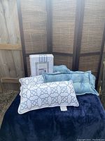 Photo of the bedding set with duvet cover and decorative pillows laid out on a dark surface with a wooden screen behind.