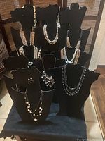 Full lot of costume jewelry displayed on black necklace busts showing multi-strand faux pearl and stone necklaces with varying lengths and styles.