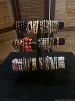 Front view of the 44 assorted costume stretch bracelets on black display stand showing multiple rows and colors.