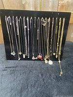 Photo showing the full set of 17 costume necklaces arranged on a black velvet display, highlighting the variety of pendants including hearts, purse, flip flop, layered designs, and small charms.