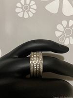 Ring displayed on black mannequin hand showing the four rows of Swarovski crystals around the band.