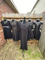 Six black female mannequins dressed in six different black dresses showcasing variety of styles and details such as sequin waist, lace waistband, gold zipper and ruffle shoulder.