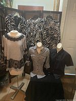 Photo showing group of 8 women's clothing items on mannequins and hangers including patterned tops and jackets