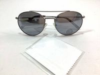 Front view of Joe Fresh metal frame sunglasses with gray lenses and included white lens cleaning cloth in plastic sleeve.