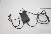 Black Nintendo GameCube power supply with power cables laid out showing adapter body and cord arrangement.