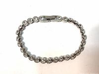 Small size tennis bracelet featuring clear Swarovski crystals in white rhodium plated metal setting, shown laid flat with clasp visible.