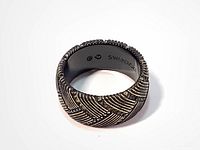 Close-up photo of the Swarovski men's ring showing the side view of the wide band with geometric pattern and embedded tiny crystals.