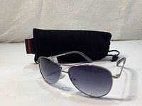 Side angled view of the Joe Fresh aviator sunglasses with Bolle pouch behind.