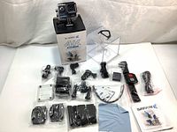 Full kit laid out with Safari 3 4K 30fps WiFi action camera on top of the box, surrounded by mounts, charging cable, remote, battery, cleaning cloth, and instruction manual.