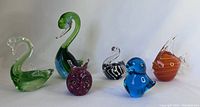 Six Italian glass sculptures arranged together showing the variety of colors and animal shapes.