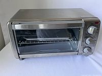 Front angled view of Black & Decker stainless steel toaster oven showing glass door, interior rack, and handle