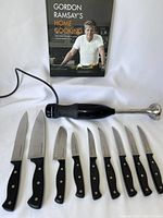Photo showing the entire set: KitchenAid immersion blender, 9 kitchen knives with black handles, and Gordon Ramsay's Home Cooking cookbook.