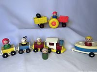 Full set of vintage Fisher Price Little People, including tractor with trailer, train cars with figures, and boat on trailer.