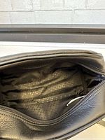 View inside the bag showing the black interior lining with branded pattern and spacious main compartment.