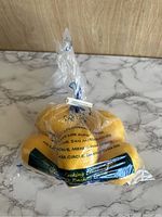 Six yellow imitation plastic lemons in two sealed plastic bags on a marble surface.