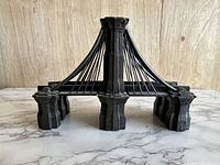 Front view of one cast iron Brooklyn Bridge bookend showing the detailed suspension cable design and sturdy base.