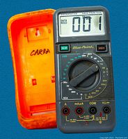 Digital multimeter showing front view with orange rubber protective case detached, featuring display reading '001' and rotary dial for various measurements.