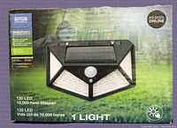 Box for Dotcom Products Black LED Solar Interaction Wall Lamp with solar panel on top and 120 LED lights indicated on front