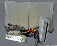 Nintendo Wii console, remotes, cables, and balance board laid out together showing included items.