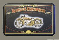 Top view of rectangular black tin with vintage motorcycle image and Harley-Davidson logo on lid
